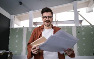 Čovek drži papire dok stoji u prostoriji koja se renovira