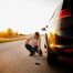 muskarac proverava gume na automobilu pred put